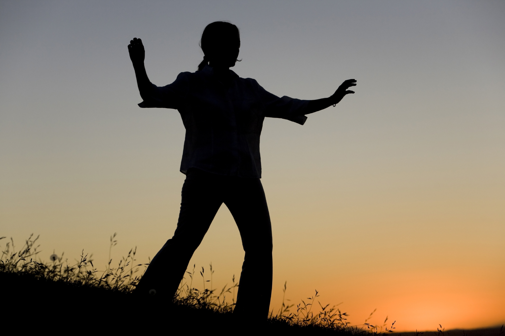 Shadowy figure doing Tai Chi against sunset background