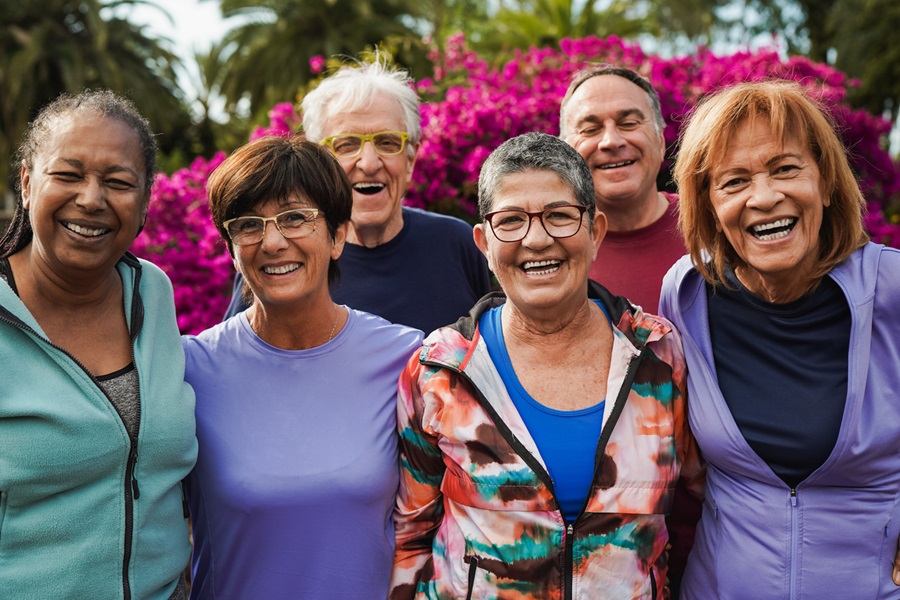 Group of seniors posing for a picture after an exercise class outdoors.