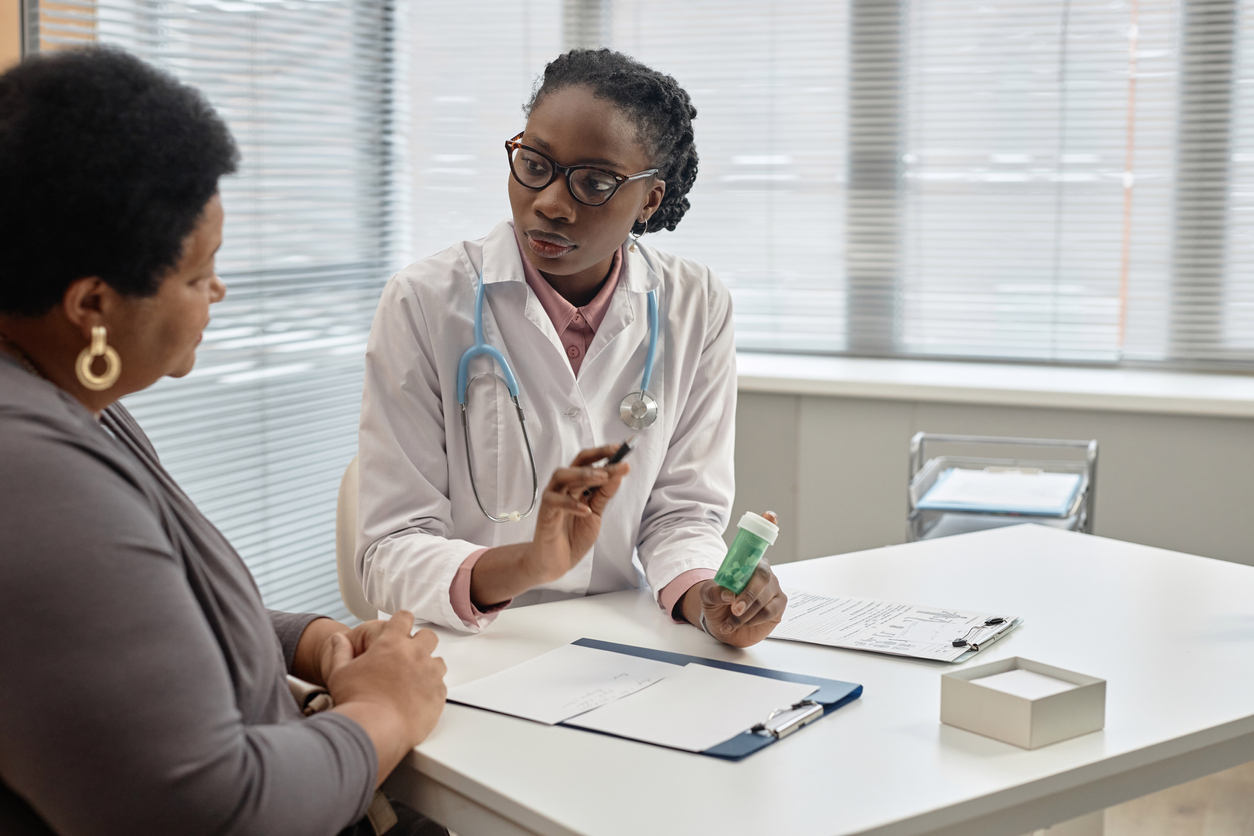 Doctor holding a medication bottle and consulting with patient.