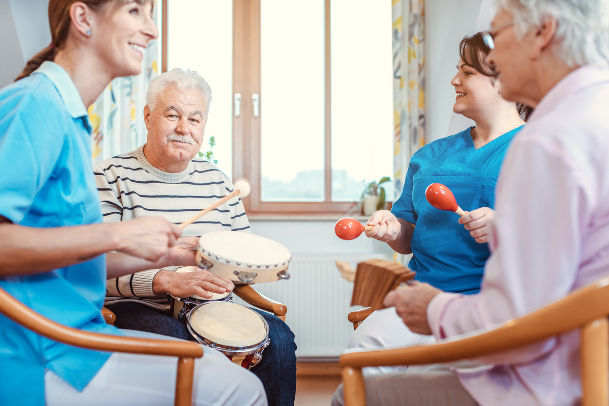Two older adults and two caregivers sitting in a circle and playing instruments.