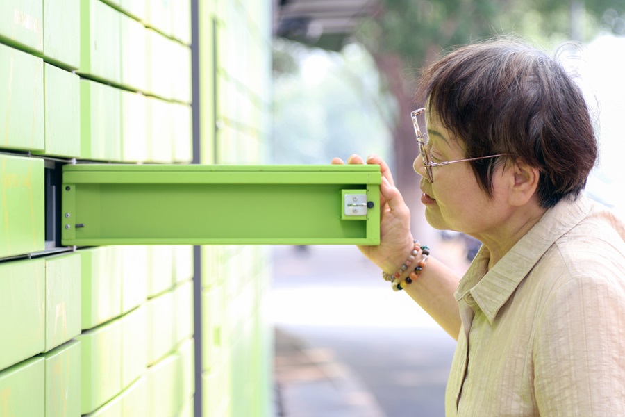 Older adult looking into opened mailbox.